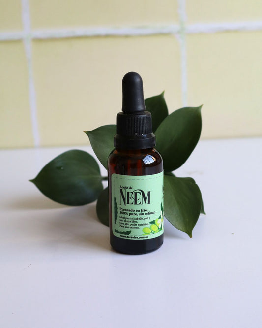Frasco de aceite de neem prensado en frío junto a hojas verdes