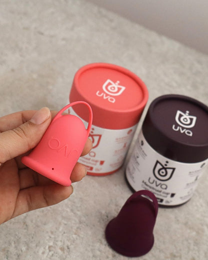 Copa menstrual talla salmón sostenida en la mano
