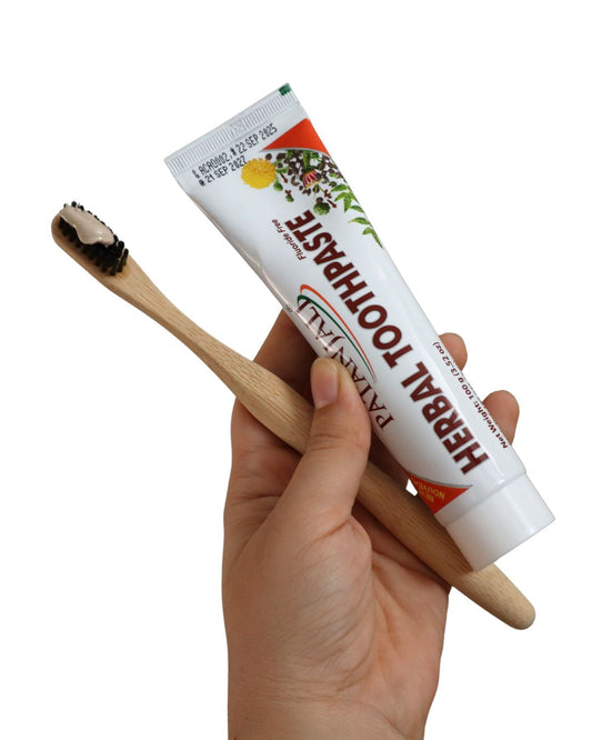 Mano aplicando crema dental herbal Patanjali en el cepillo