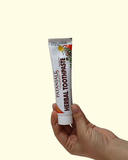 Mano sosteniendo el tubo de crema dental herbal Patanjali