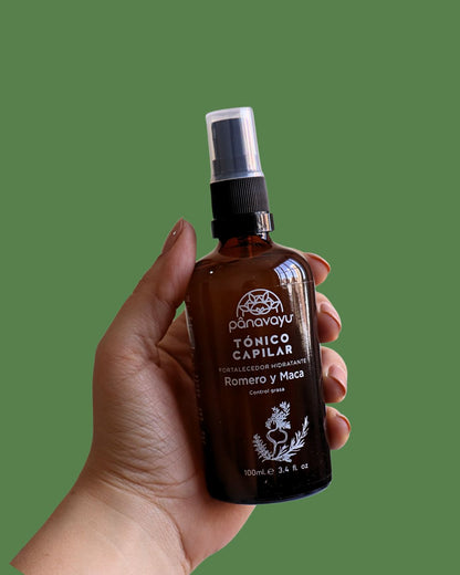 Frasco spray tónico capilar Panavayu aplicado en cuero cabelludo, fondo verde