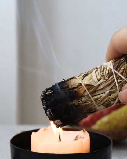 Yerba santa encendida junto a una vela en cuenco